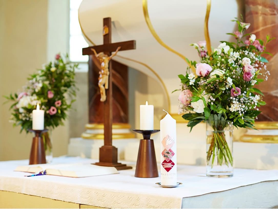 Altar für die Erstkommunion dekoriert mit Kerzen, Blumen und einem Kreuz