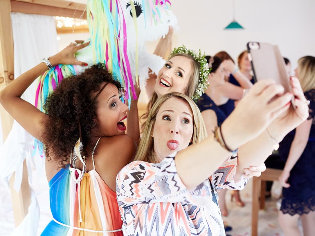 Drei Frauen machen ein Selfy an einer Piñata und ziehen Grimassen