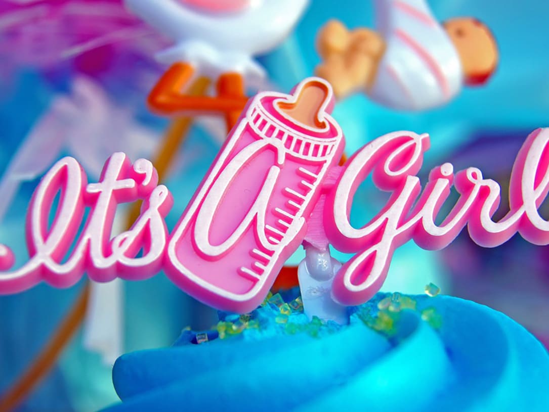 Rosafarbener schriftzug "It's a Girl" mit Fläschchen als Aufsatz einer Torte