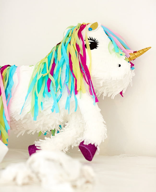 Weiße Einhorn-Piñata mit goldenem Horn und bunter Mähne