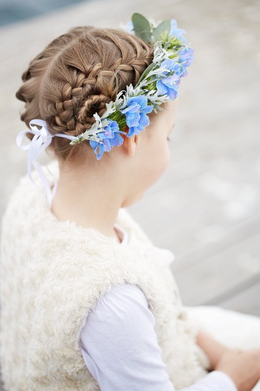 Mädchen mit geflochtenem Haar und einem hübschen Blumenkranz von hinten fotografiert