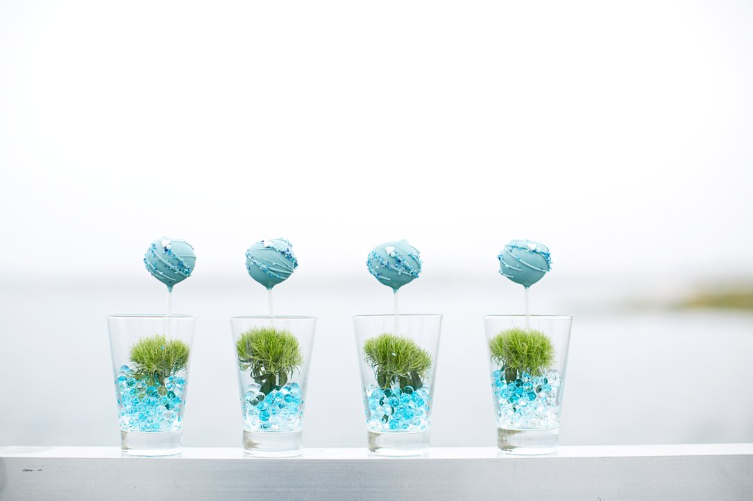 4 Gläser mit Bubbles und Pflanzen und hellblauen Cakepops