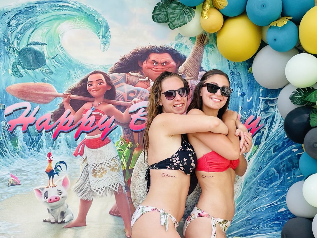 Zwei Mädchen stehen in Bikini vor einem Vaiana-Poster und Luftballons